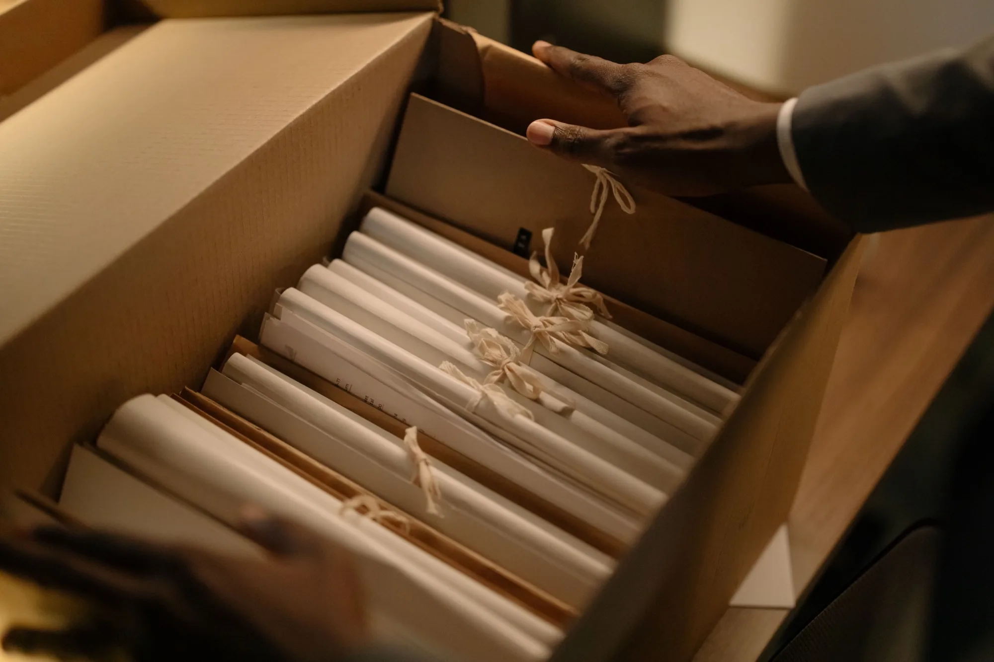 Hand lifting the lid from a box of tied document bundles